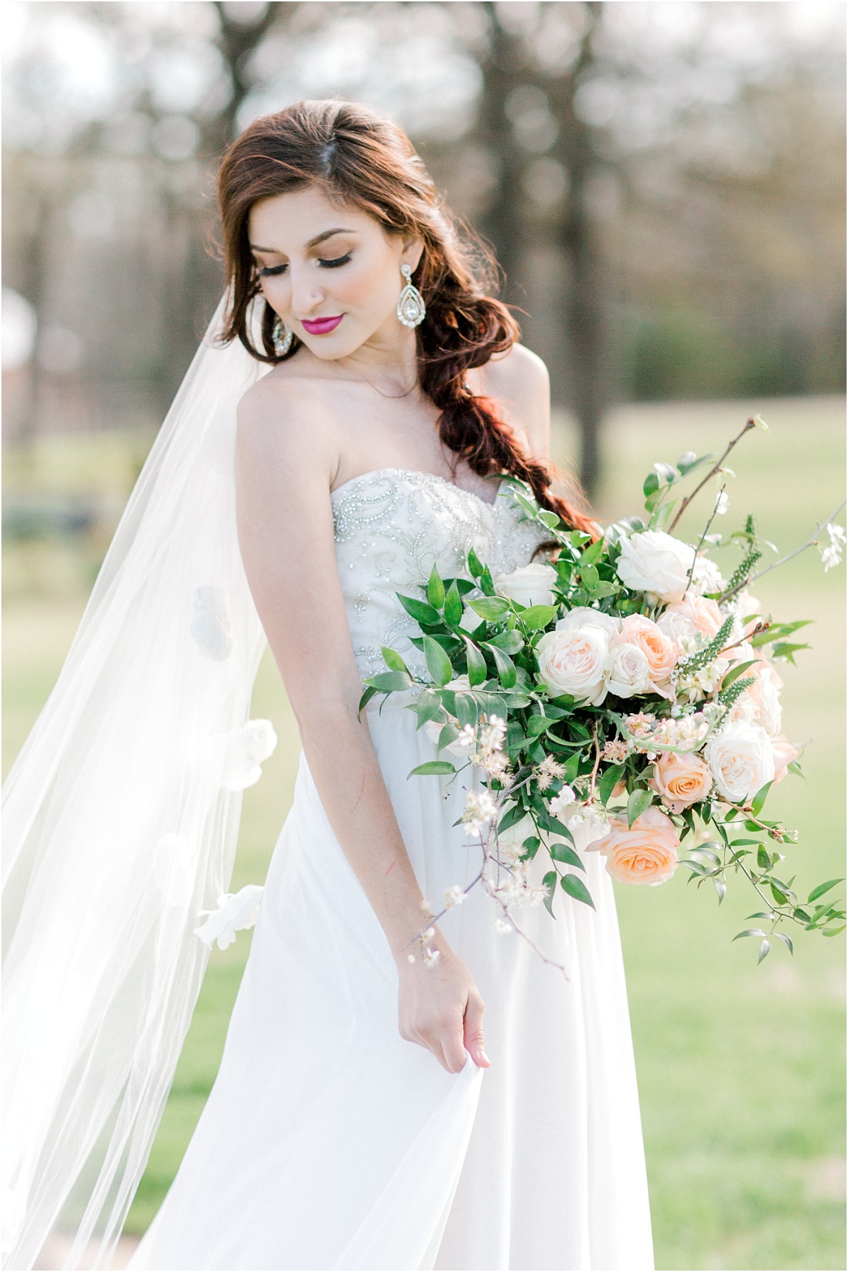 Bride in an lace and ivory bridal gown standing on the lawn of the White Sparrow Barn in Quinlan, Texas. 