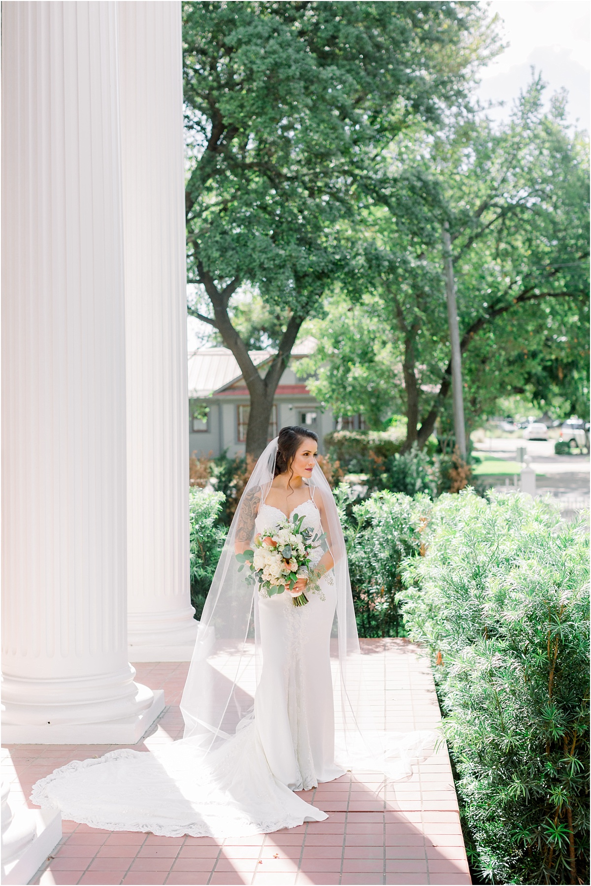 Bride standing on the front porch of the Woodbine Mansion holding her bouquet. 