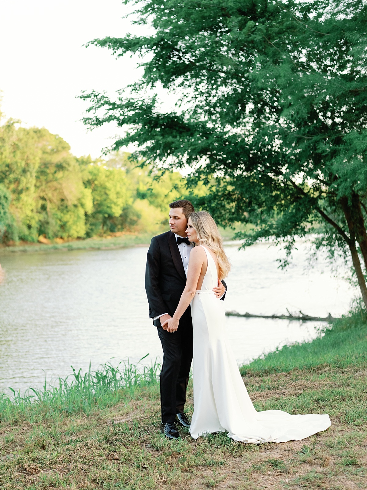Bride and Groom standing near the river in their wedding attire.