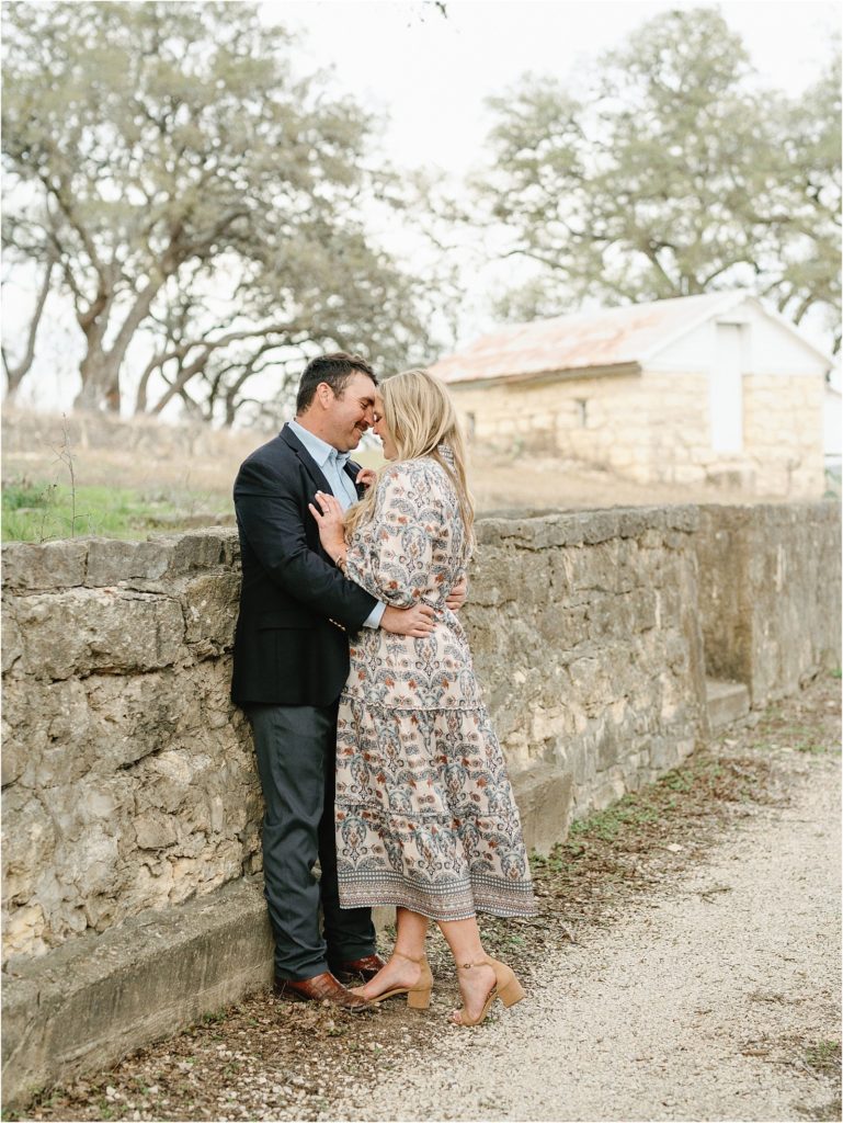 Couple embracing against a rock wall during their San Antonio engagement photos.