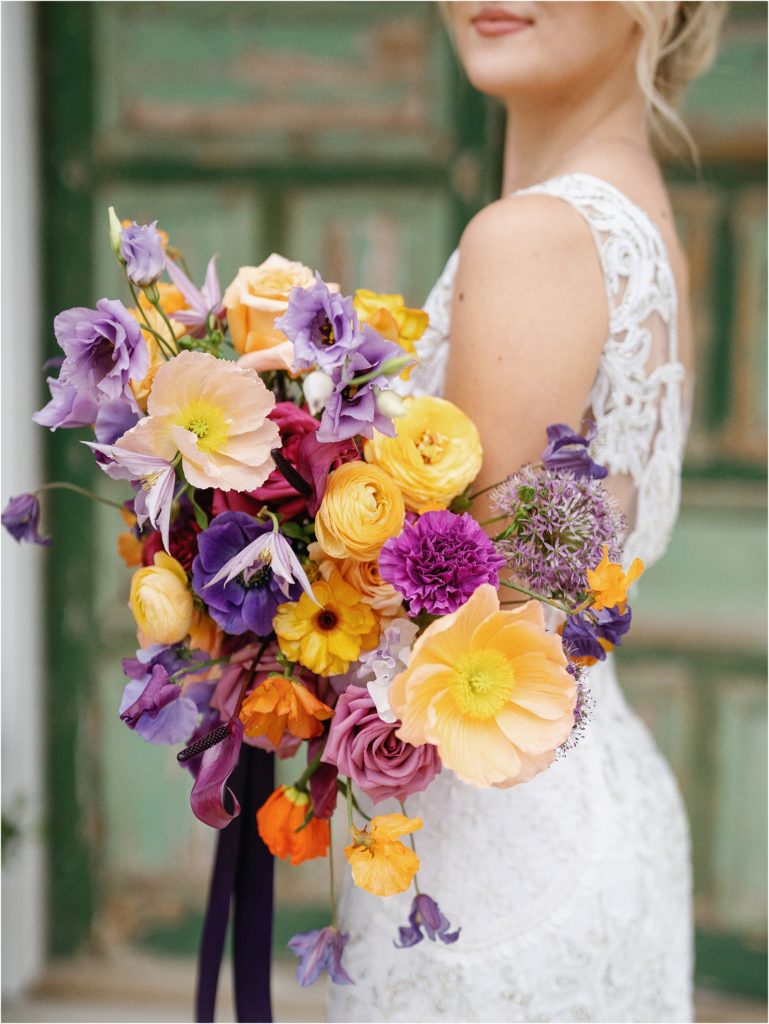 Bride holding a colorful wedding bouquet in front of the bridal suite at The Videre Estate.