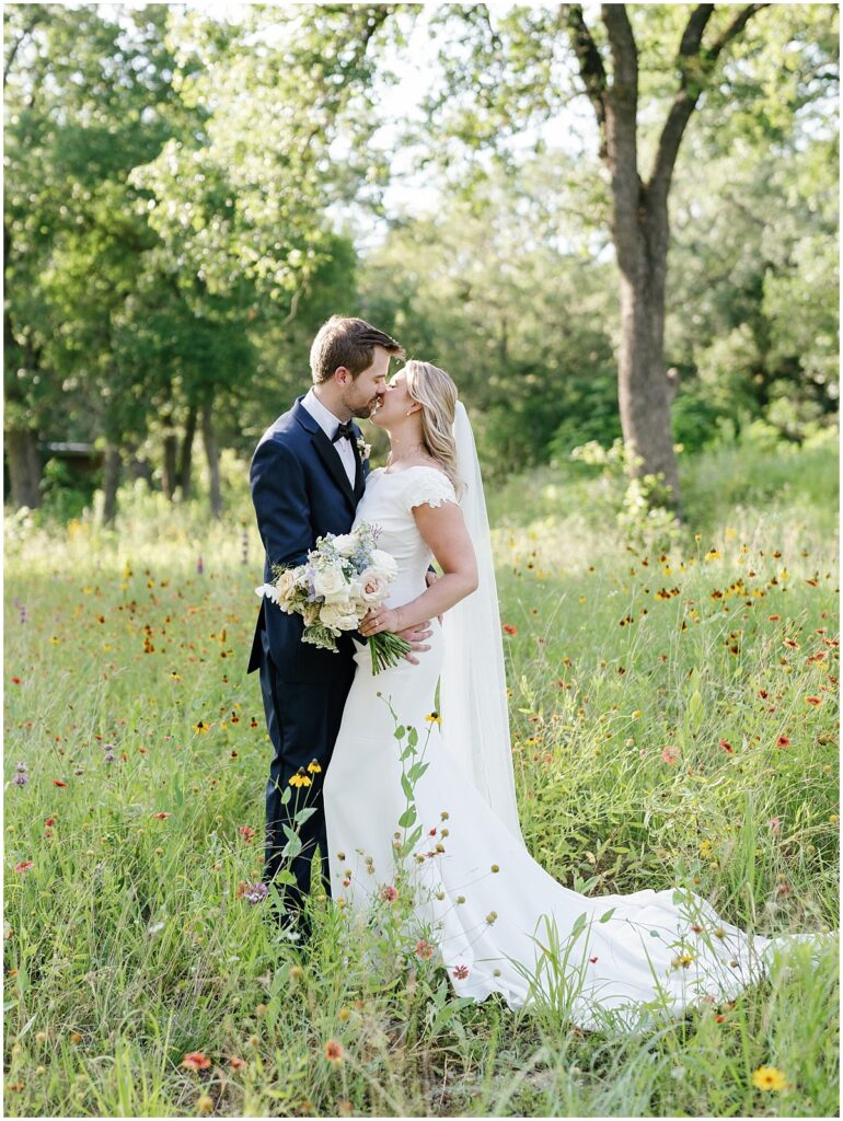 Bride and Groom kissing under the oak trees at The Grand Lady wedding venue in Austin, TX.