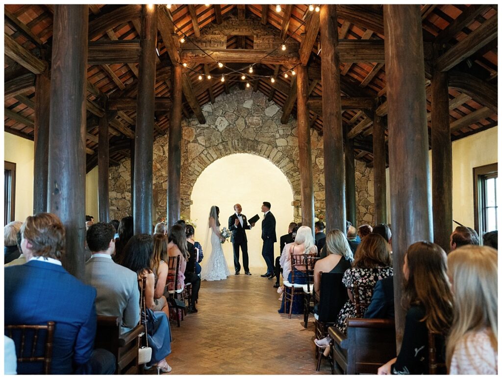 Savana and Casey stand together at the altar inside Ian's Chapel, listening to the officiant during their wedding ceremony.