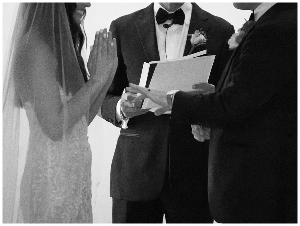 Savana gently places the ring on Casey's finger during the ring exchange inside Ian's Chapel, both smiling with joy.