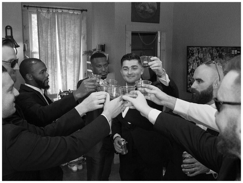 Casey and his groomsmen laughing and preparing in the rustic groom's suite at Camp Lucy