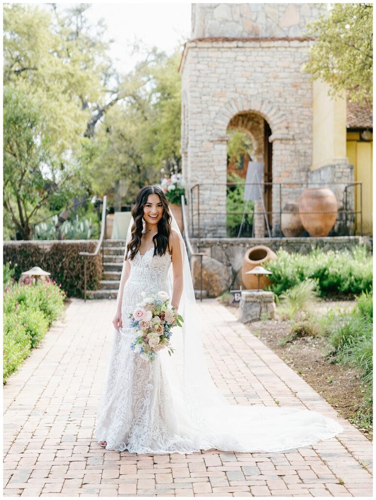 The bride stands under the ancient oak trees near Ian's Chapel, holding her bouquet and looking serene